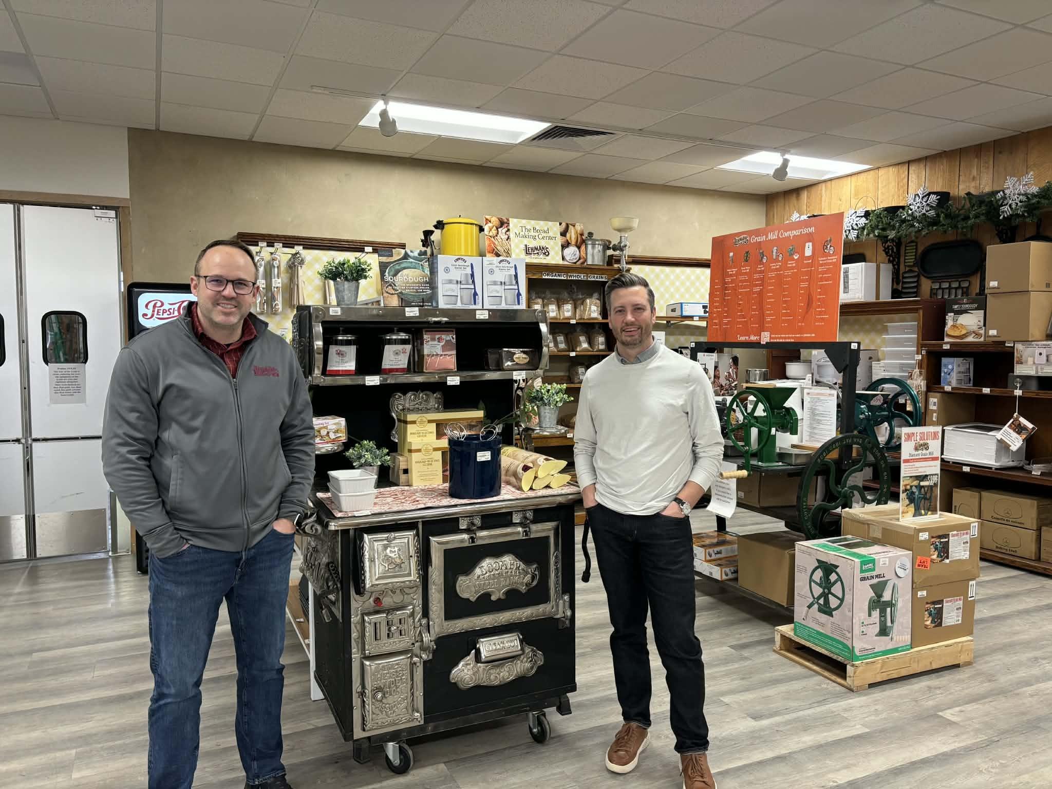 Zach Coblentz (L) and Cameron O'Neill (R) stand next to grain mills and breadmaking items at Lehman's in Kidron, Ohio, on Feb. 11, 2026. (Jeff Louderback/Epoch Times)