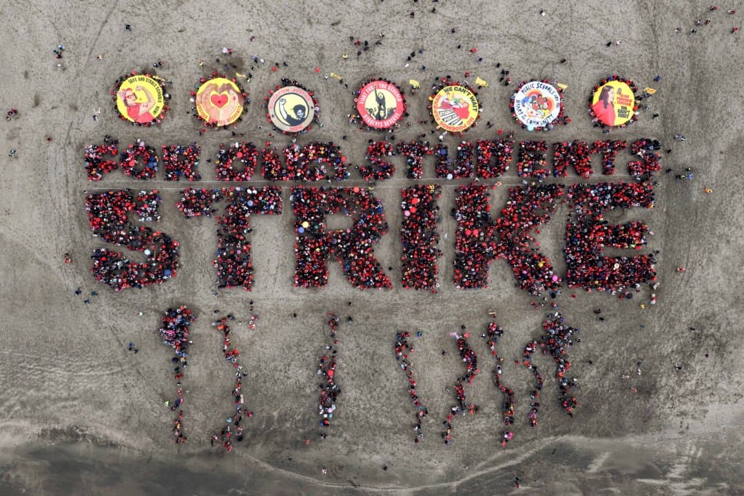 San Francisco Unified School District teachers and students form a human banner spelling out “Strike” at Ocean Beach in San Francisco on Feb. 11, 2026. Nearly 6,000 educators in the San Francisco Unified School District are on strike for a third day, the city’s first teachers’ strike in almost 50 years, after contract talks have collapsed over wages, health benefits, and staffing, leaving all 120 district schools closed as negotiations continue. (Justin Sullivan/Getty Images)
