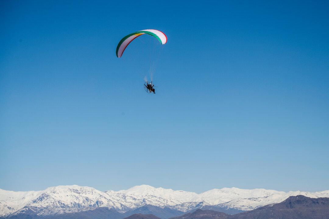 A paramotorist using a wing in the colors of the Kurdish flag flies over the Korek Mountain resort near the city of Rawanduz in Iraq's northern autonomous Kurdish region, during the Kurdistan Ice and Snow festival on Feb. 16, 2026. (Safin Hamid/AFP via Getty Images)