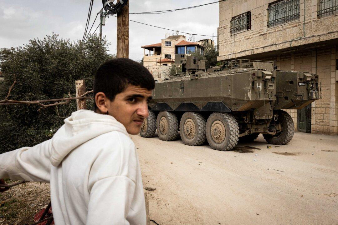 A Palestinian man stands next to an Israeli armored vehicle during a military raid in al-Yamun town west of Jenin in the West Bank, on Feb. 17, 2026. (John Wessels/AFP via Getty Images)