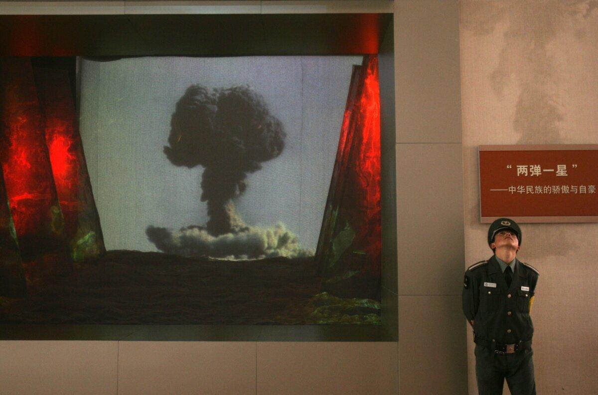 A security guard stands beside a screen showing a video about China's atomic and hydrogen bomb research during an exhibition on the Chinese regime's rejuvenation at the Military Museum of the Chinese People's Revolution in Beijing on Oct. 17, 2007. (China Photos/Getty Images)