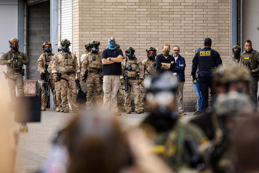 Federal agents monitor protestors as they gather in front of Immigration and Customs Enforcement offices in Portland, Ore., on Oct. 4, 2025. (John Fredricks/The Epoch Times)