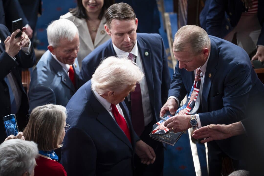 President Trump signs a tie as he leaves. (Madalina Kilroy/The Epoch Times)