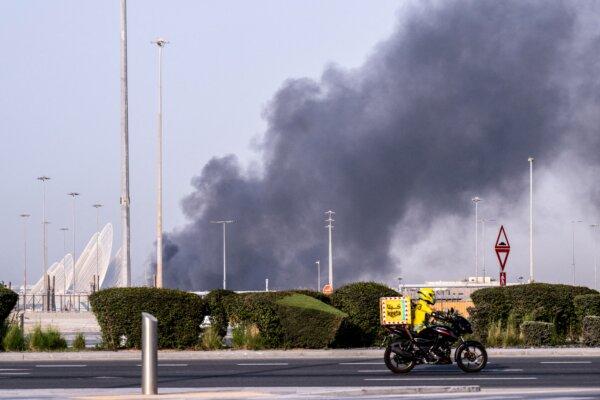 A food delivery bike drive close to a plume of smoke rising from the Zayed Port following a reported Iranian strike in Abu Dhabi, U.A.E., on March 1, 2026. (Ryan Lim / AFP via Getty Images)