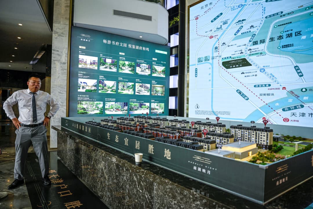 A salesperson standing next to a housing estate model at a property sales center in Tianjin, China, on June 5, 2024. China’s property market remains a major drag on growth, with all 70 large and medium-sized cities tracked by the National Bureau of Statistics still recording monthly declines in secondhand home prices as of December 2025. (Jade Gao/AFP via Getty Images)