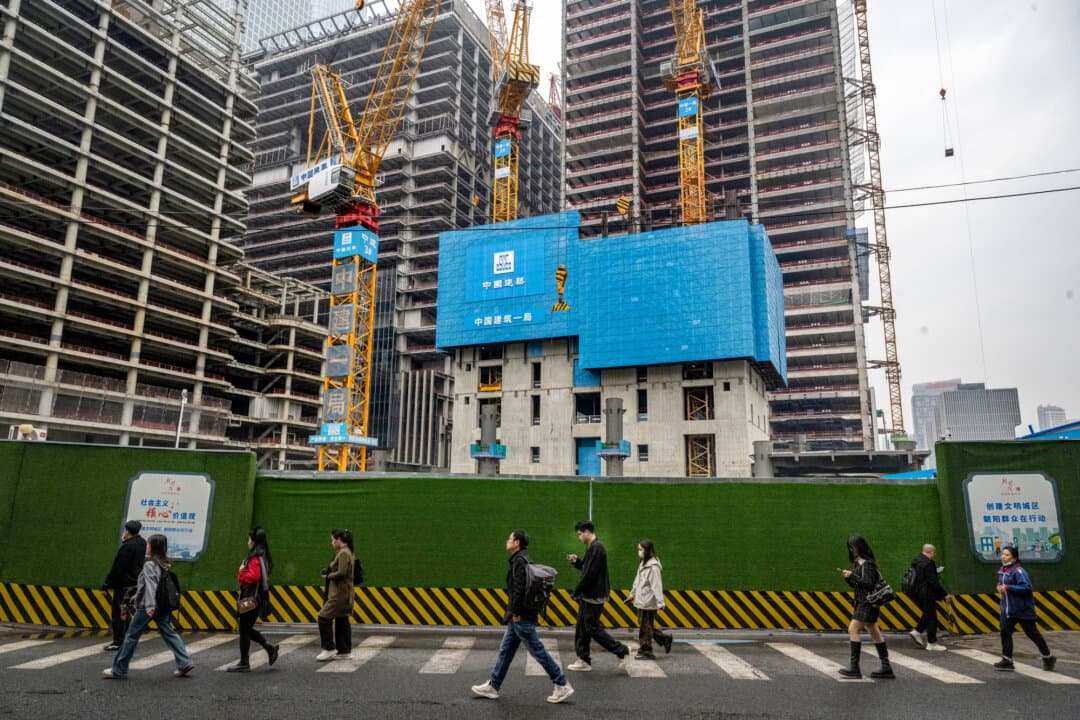 Commuters walk by new office towers under construction as they head to work in the Central Business District in Beijing on Oct. 18, 2024. Investment in fixed assets such as buildings and equipment fell by 3.8 percent in 2025, while private investment dropped by 6.4 percent. (Kevin Frayer/Getty Images)