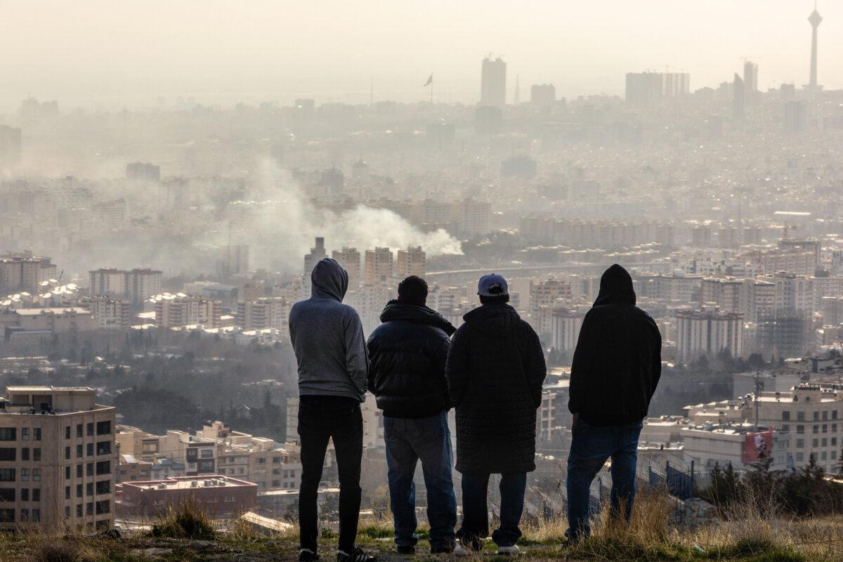 Men watch from a hillside as a plume of smoke rises after an explosion in Tehran, Iran, on March 2, 2026. (Majid Saeedi/Getty Images)