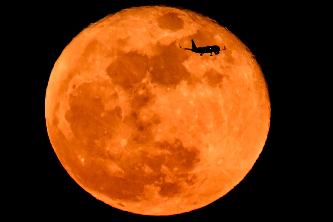 Airbus A320-214 aircraft of German airline Lufthansa flies past the waning gibbous moon over Frankfurt am Main, Germany, on March 4, 2026. (Kirill Kudryavtsev/AFP via Getty Images)