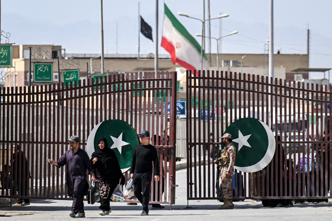 Pakistani nationals walk across the Taftan border in Balochistan province as they return from Iran on March 4, 2026, amid ongoing U.S.-Israel strikes on Iran. Pakistani nationals hauled suitcases across the border from neighboring Iran, describing missiles being launched and travel chaos as they scrambled to leave the country that the United States and Israel attacked over the weekend. (Banaras Khan/AFP via Getty Images)
