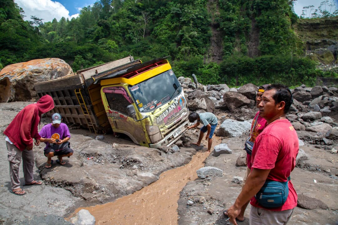 Residents attempt to recover parts of trucks buried in sand after a rain-triggered mudflow from Mount Merapi left three people dead in the Senowo River in Magelang, Central Java, Indonesia, on March 4, 2026. (Devi Rahman/AFP via Getty Images)