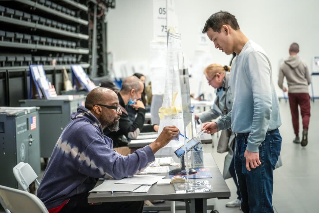 A voter shows his photo identification to poll workers as he arrives to cast his midterm election ballot in New York City on Nov. 8, 2022. (Samira Bouaou/The Epoch Times)