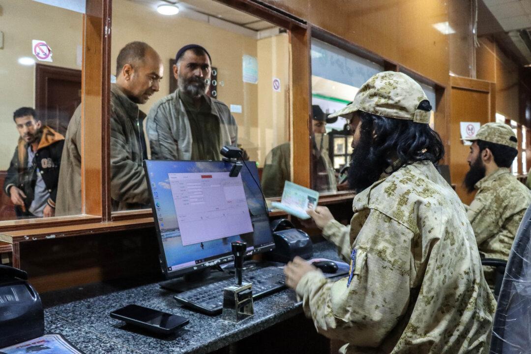 Taliban security personnel check passports of Afghan nationals upon their arrival from Iran at the Islam Qala border crossing in Herat province on March 5, 2026. (Mohsen Karimi/AFP via Getty Images)