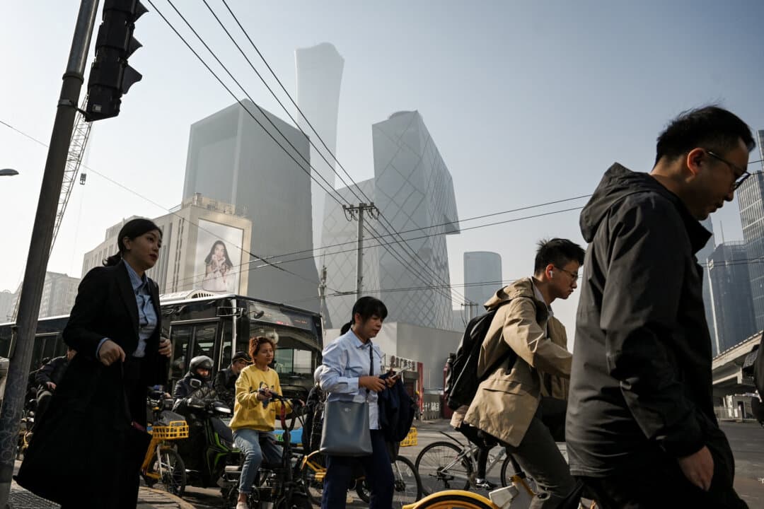 People cross a road on their way to work in Beijing’s central business district on April 10, 2025. (Greg Baker/AFP via Getty Images)