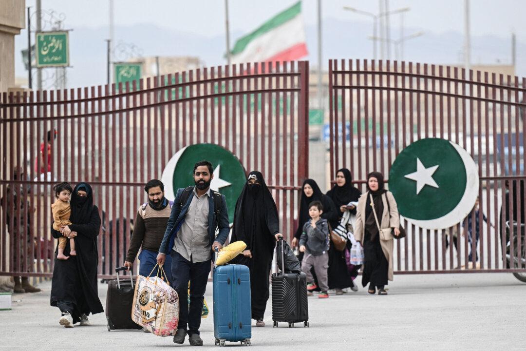 Pakistani nationals walk across the Taftan border as they return from Iran, in Balochistan province, Pakistan, on March 6, 2026. Pakistani nationals hauling suitcases were describing missiles being launched and travel chaos as they scrambled to leave the country that the United States and Israel hit with airstrikes over the last weekend. (Banaras Khan/AFP via Getty Images)