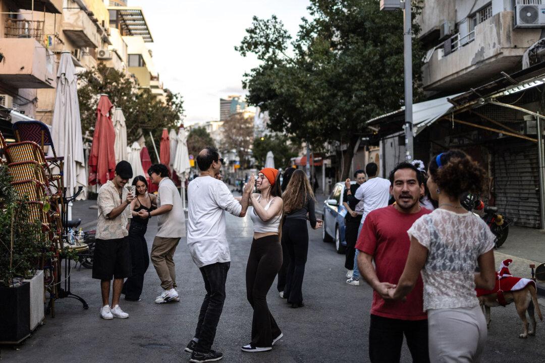 Residents dance outside a cafe along the street at Carmel market in Tel Aviv, Israel, on March 6, 2026. Israel's military said Iran had launched cluster bombs multiple times since the start of the conflict that began with U.S.–Israeli airstrikes on the Islamic republic last week. (Olympia de Maismont/AFP via Getty Images)