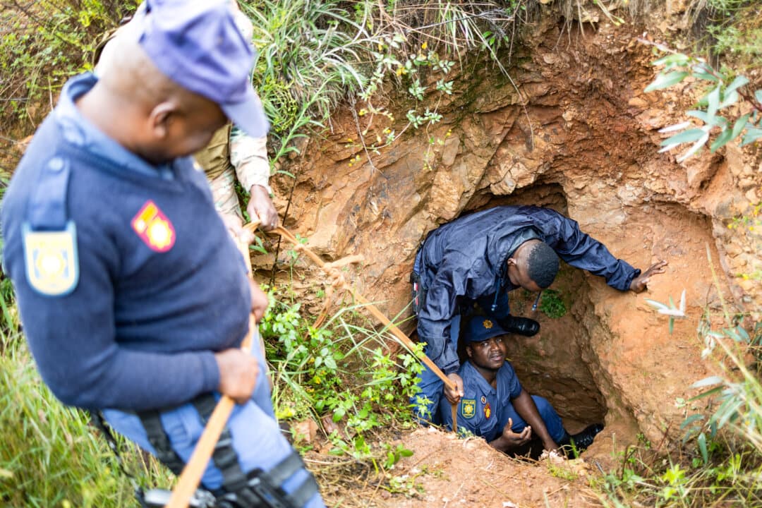 Officers of the South Africa Police Service and a soldier of the South African National Defence Force recover a generator left behind by artisanal miners, during a patrol in Randfontein, South Africa, on March 12, 2026. (Emmanuel Croset/AFP)
