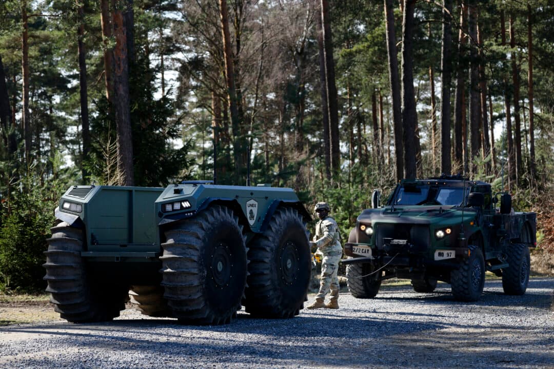 An American soldier hitches an MRAP vehicle to an Abris Design Group Unex UGV for towing during a demonstration of capabilities at the xTech Edge Strike: Ground robotics technology evaluation of the U.S. Army at the training grounds near Grafenwoehr, Germany, on March 13, 2026. The 2nd Cavalry Regiment has been hosting the competition, in which soldiers have been testing unmanned ground vehicles (UGVs) from a variety of manufacturers in realistic scenarios since March 3 to assess future procurement options of ground-based drones. (Sean Gallup/Getty Images)
