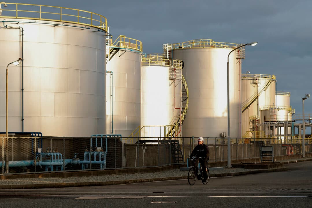 An employee rides his bicycle in front of the oil storage tanks at a Kobe Oil Terminal in Kobe, Japan, on March 13, 2026. Japan will release oil reserves to address the rise in gasoline and other petroleum products prices starting on Monday, said Prime Minister Takaichi Sanae. The International Energy Agency (IEA) stated that its member countries agreed to release the largest volume of emergency oil reserves in its history, responding to the disruption in energy markets caused by the Middle East war. (Buddhika Weerasinghe/Getty Images)