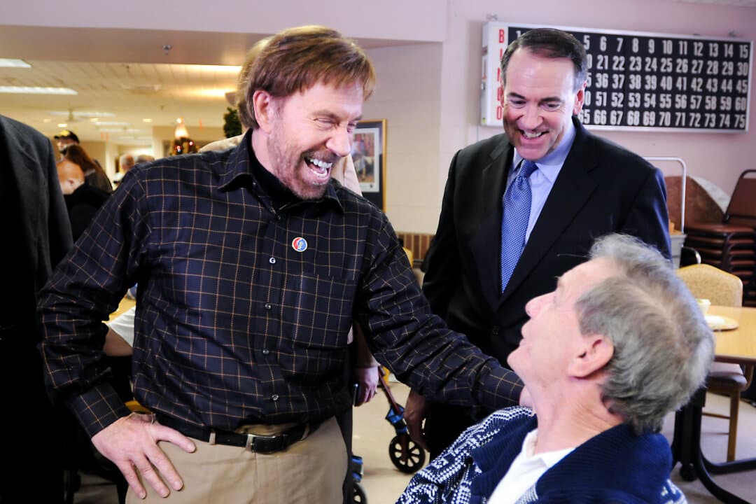 Actor Chuck Norris (L) speaks with a senior citizen while Republican Presidential hopeful former Arkansas Gov. Mike Huckabee (C) looks on at the New Hampshire Veterans Home in Tilton, N.H., on Dec. 14, 2007. Huckabee, riding impressive poll numbers, is on a three-day swing through the Granite State with Norris. (Darren McCollester/Getty Images)