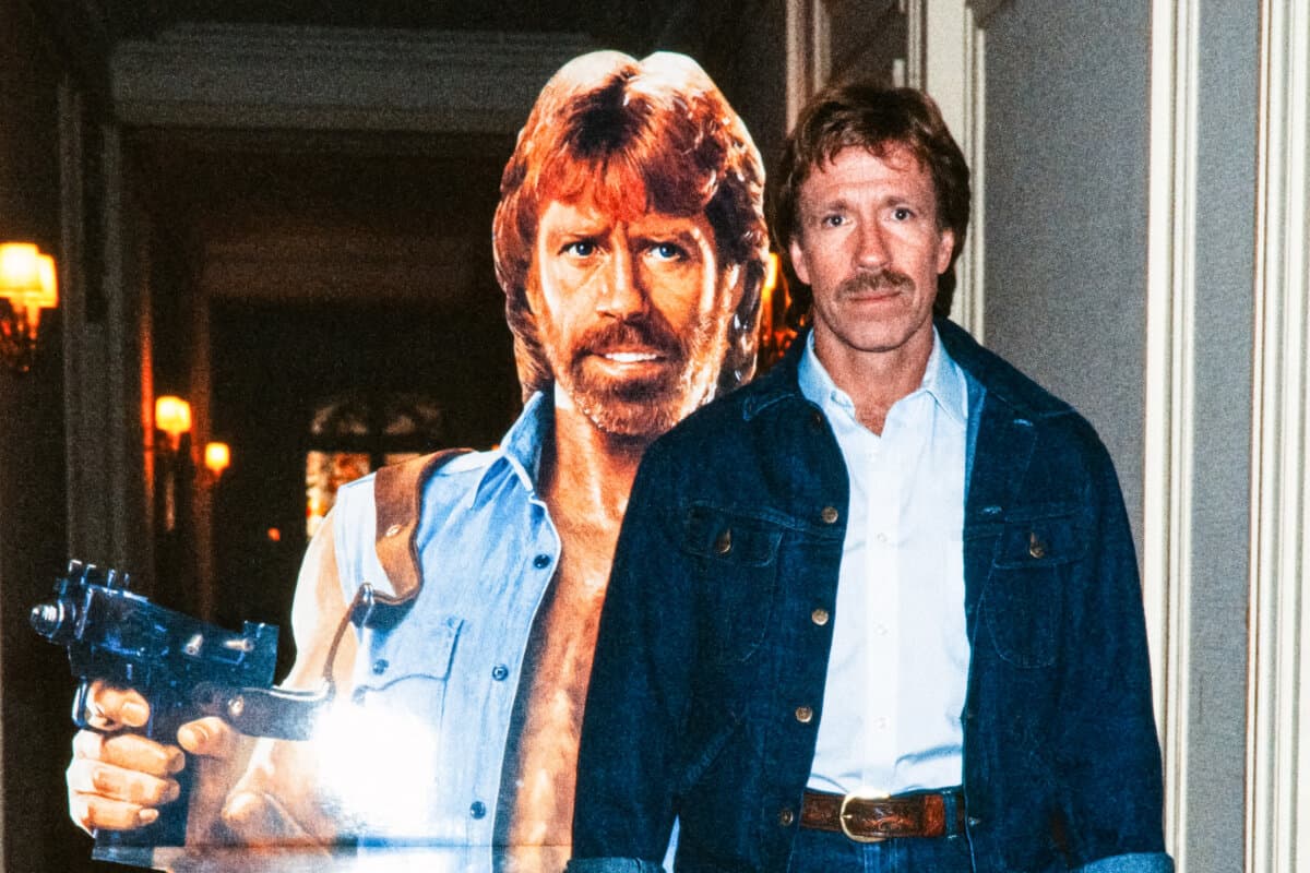 Chuck Norris poses in front of the poster for the movie "Invasion USA" at the Hôtel Plaza Athénée in Paris on Nov. 27, 1985. (Pierre Verdy/AFP via Getty Images)