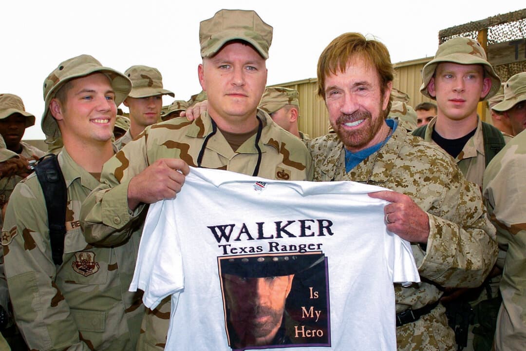 Actor and martial artist Chuck Norris (R) holds up a T-shirt presented by USAF TSgt. Mike Haddock of Florence, Alabama, during a meet-the-troops stop at Ali Al Saleem Air Base, Kuwait, on Oct. 29, 2006. Norris, best known for his role in “Walker, Texas Ranger,” is on a week-long USO tour to boost morale among U.S. troops in the region. (USO/Mike Theiler/HO/Reuters)