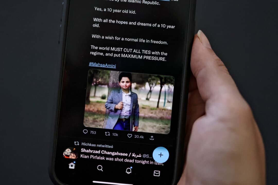 A woman looking at a social media post on her phone screen reportedly showing an Iranian boy who was killed in a shooting attack in November 2022, in the western Iranian town of Izeh, in Nicosia, Cyprus, on Nov. 18, 2022. (-/AFP via Getty Images)
