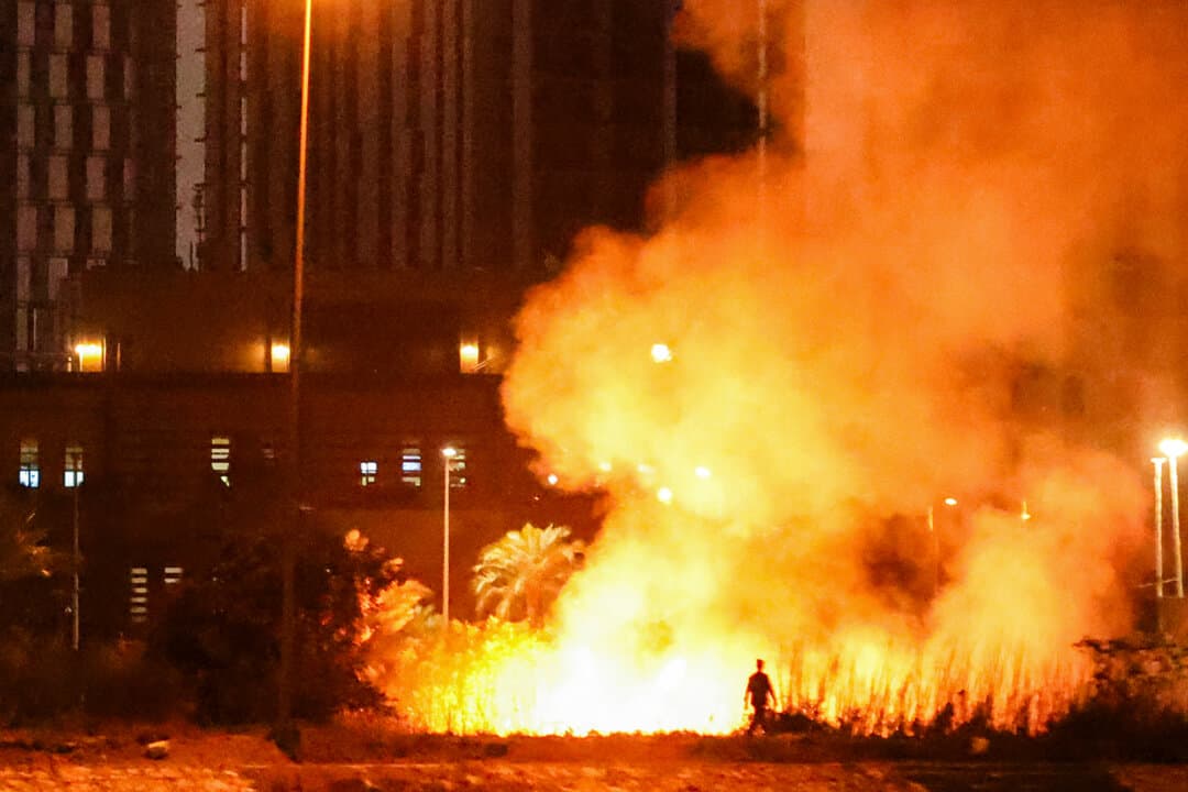 A person walks near a fire burning outside the U.S. Embassy compound following a drone and rocket attack in the fortified Green Zone in Baghdad, Iraq, on March 17, 2026. (Ahmad Al-Rubaye/AFP via Getty Images)