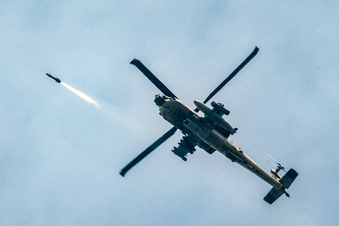 An Israeli Air Force AH-64 Apache attack helicopter fires rockets along the Israel–Lebanon border on March 18, 2026. On March 19, U.S. Secretary of War Pete Hegseth said joint U.S. and Israeli strikes had targeted Iranian drone production facilities, with launches of one-way attack drones down about 90 percent from their peak. (Jalaa Marey/AFP via Getty Images)