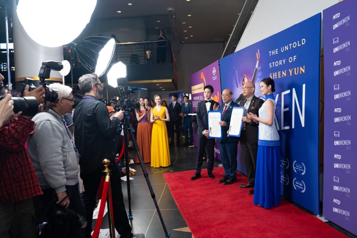 New York City Council member Phil Wong (2nd L) and constituent services liaison Bernard Chow (2nd R) present a proclamation for Shen Yun Performing Arts alongside Shen Yun principal dancers Piotr Huang (L) and Angelia Wang (R) at the worldwide premiere of "Unbroken: The Untold Story of Shen Yun" at the AMC Lincoln Square movie theater in New York City on March 24, 2026. (Samira Bouaou/The Epoch Times)