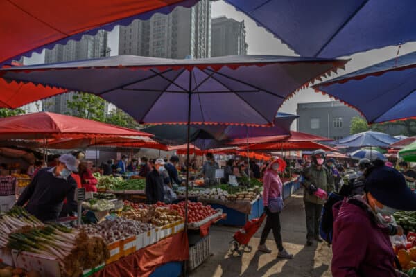 Chinese fruit and vegetable vendors and customers wear protective masks at a local outdoor market in Beijing on April 30, 2020. (Kevin Frayer/Getty Images)