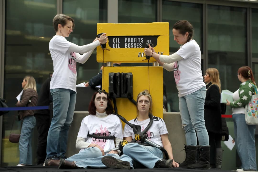 Protesters restrained to a fake fuel pump labeled Rosebank are covered in fake oil during the Fossil Free London protest outside the U.S. Embassy in London on April 1, 2026. Rosebank is an undeveloped oil field northwest of Shetland. (Alishia Abodunde/Getty Images)