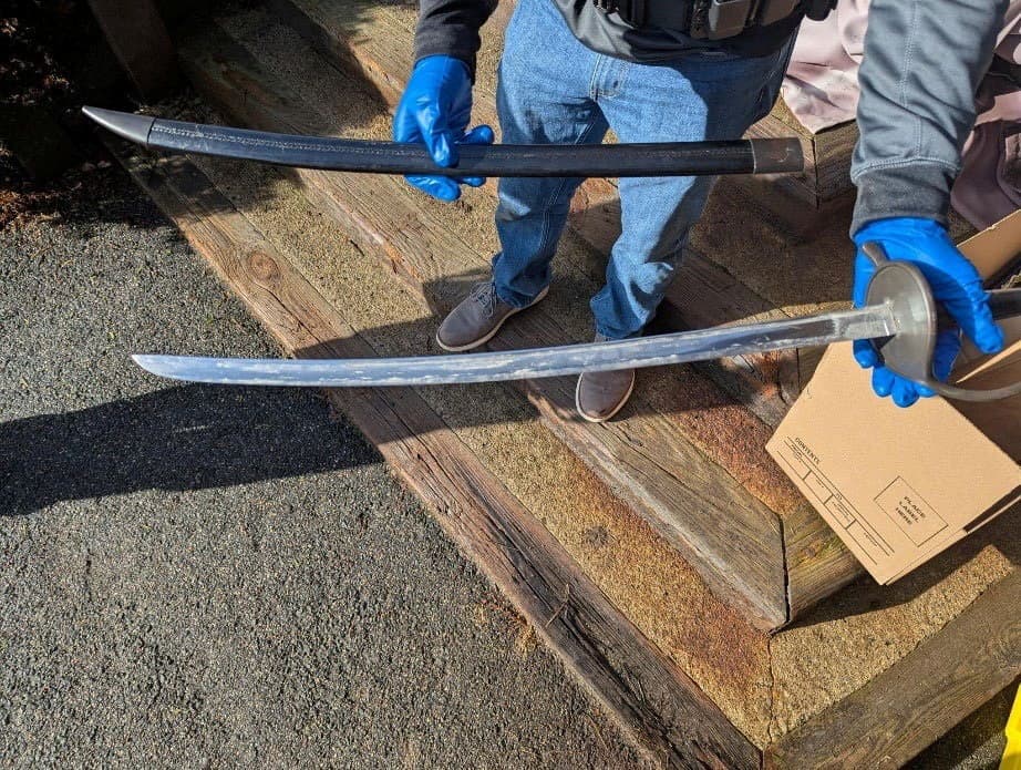 A law enforcement agent holds one of several bladed weapons seized by authorities after the arrest of Andrew Emerald in Great Barrington, Mass., on April 1, 2026, on charges that he threatened President Donald Trump in Facebook posts. (U.S. Attorney's Office for the District of Massachusetts/Handout via Reuters)