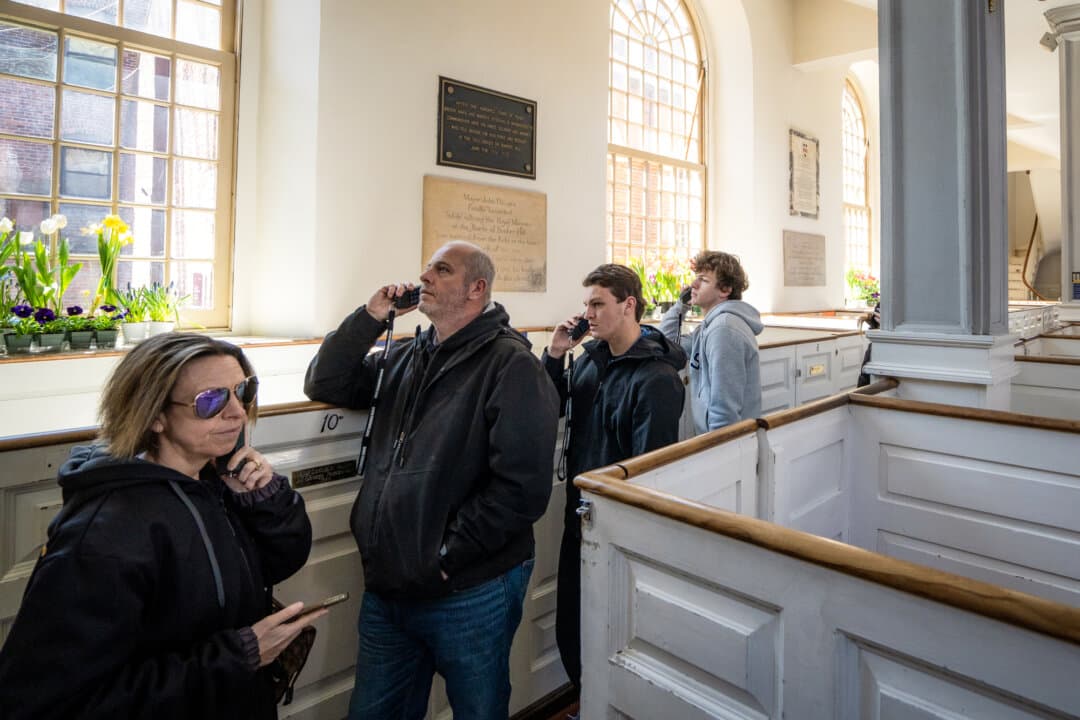 Visitors listen to handheld audio devices for self-guided tours, at Old North Church in Boston on April 8, 2026. (Samira Bouaou/The Epoch Times)
