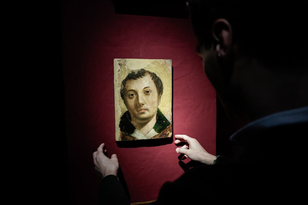 An employee handles a painting entitled “Face of a Young Saint” by artist Antonello da Messina ahead of its auction at Hotel Drouot auction house in Paris on April 2, 2026. (Stephane De Sakutin/AFP via Getty Images)