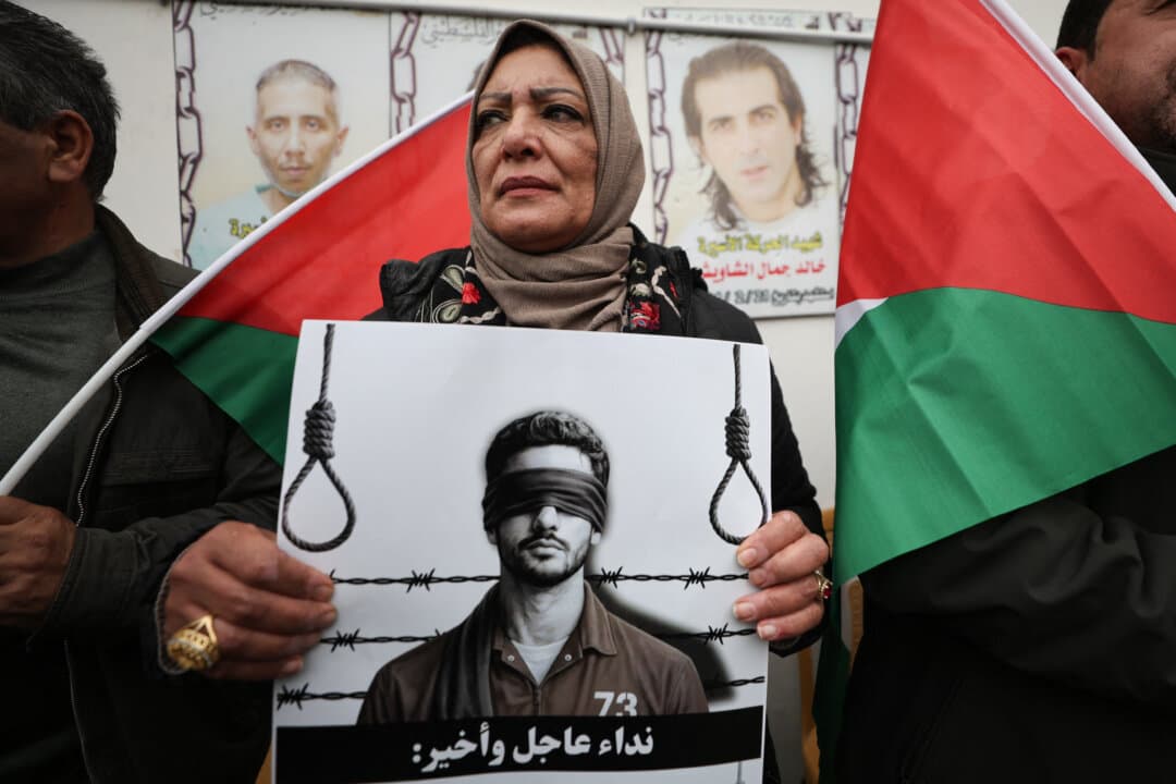 Palestinians hold posters and flags during a protest against Israel's new death penalty law outside Red Cross headquarters in Hebron in the West Bank on April 2, 2026. Israel's parliament passed the law on March 30, mandating the death penalty for Palestinians convicted of lethal attacks. (Mosab Shawer/Middle East Images/AFP via Getty Images)