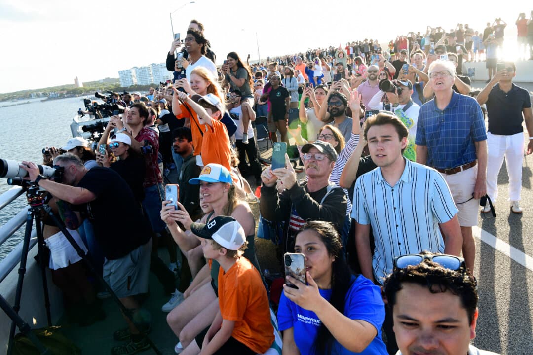 People observe the launch of Artemis II from the A. Max Brewer Bridge in Titusville, Fla., on April 01, 2026. The 322-foot-tall rocket will take astronauts around the moon and back, 230,000 miles out into space—the farthest any human has ever traveled from Earth. (Gerardo Mora/Getty Images)