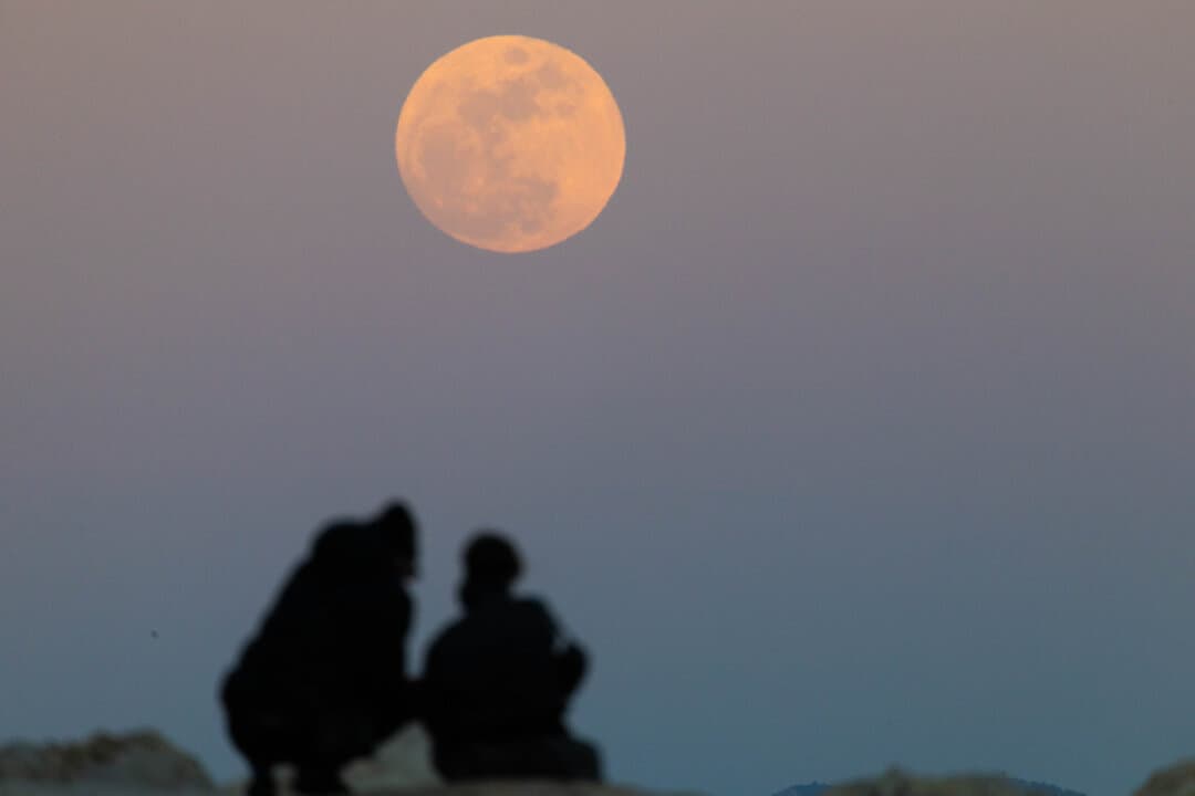 A couple watches the moon rising over Marseille, France, on April 1, 2026. (Thibaud Moritz/AFP via Getty Images)