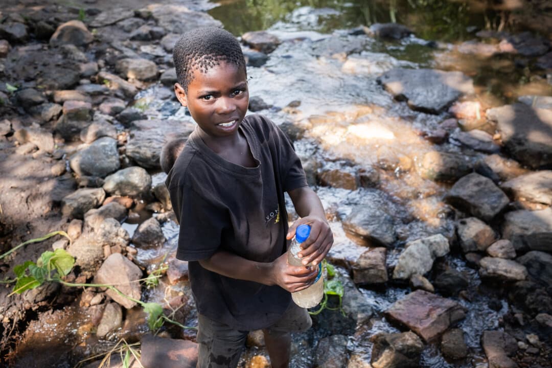 Children drink water from a polluted stream in the Mangochi District of Malawi on Feb. 19, 2026. (John Fredricks/The Epoch Times)