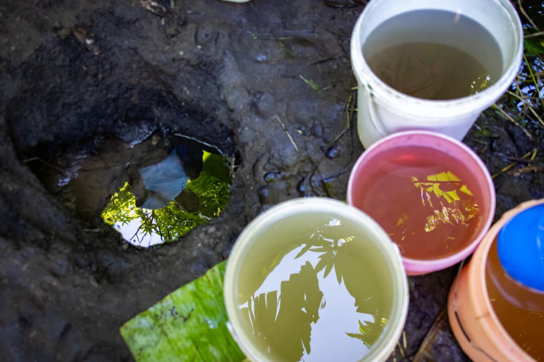 Health Surveillance Officer Duncan Chikwindile is reflected in a poor water source in the Blantyre Rural District of Malawi on Feb. 23, 2026. (John Fredricks/The Epoch Times)