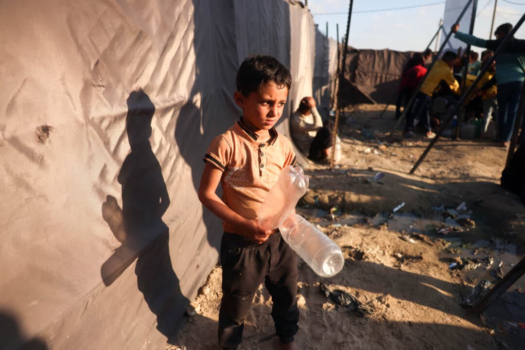 A boy holds empty plastic bottles while waiting to collect drinking water at a camp for displaced Palestinians in Khan Yunis, Gaza Strip, on April 10, 2026. (Bashar Taleb/AFP via Getty Images)