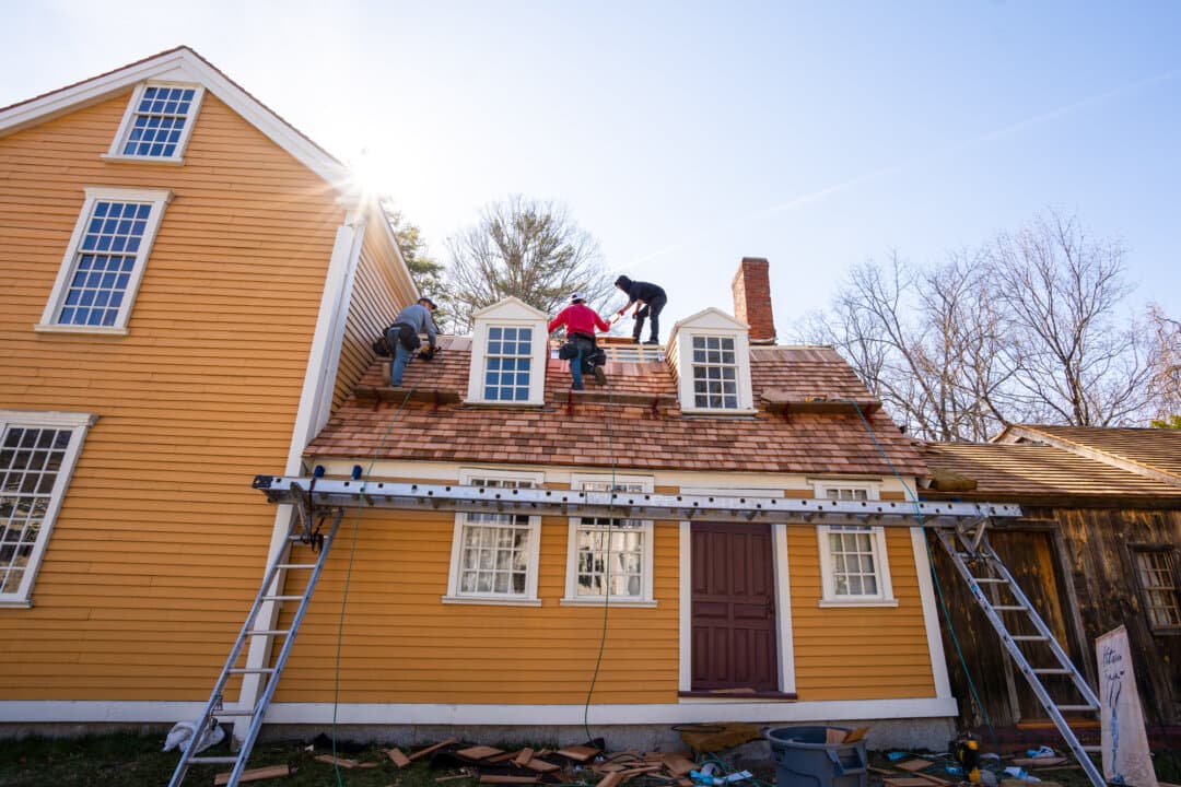 Timoteo Briceno (R) works on replacing the wood shingles on the Hancock-Clarke House in Lexington, Mass., on April 9, 2026. (Samira Bouaou/The Epoch Times)