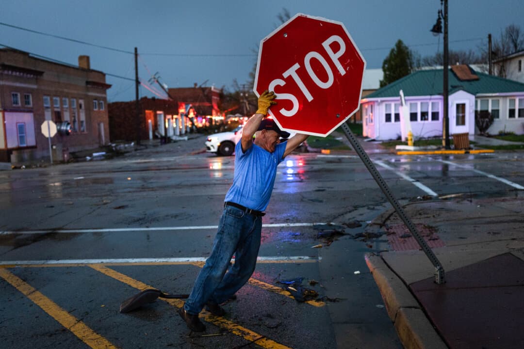 A worker straightens a stop sign that was bent over when a tornado passed through the center of town in Lena, Ill., on April 17, 2026. The storm that passed through the area was part of a strong system that caused tornadoes in several Midwestern states. (Scott Olson/Getty Images)