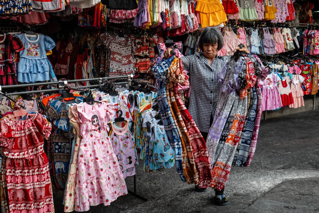A clothes vendor prepares her displays as she opens for business at Mahanak Market in Bangkok on April 20, 2026. (Anthony Wallace/AFP via Getty Images)