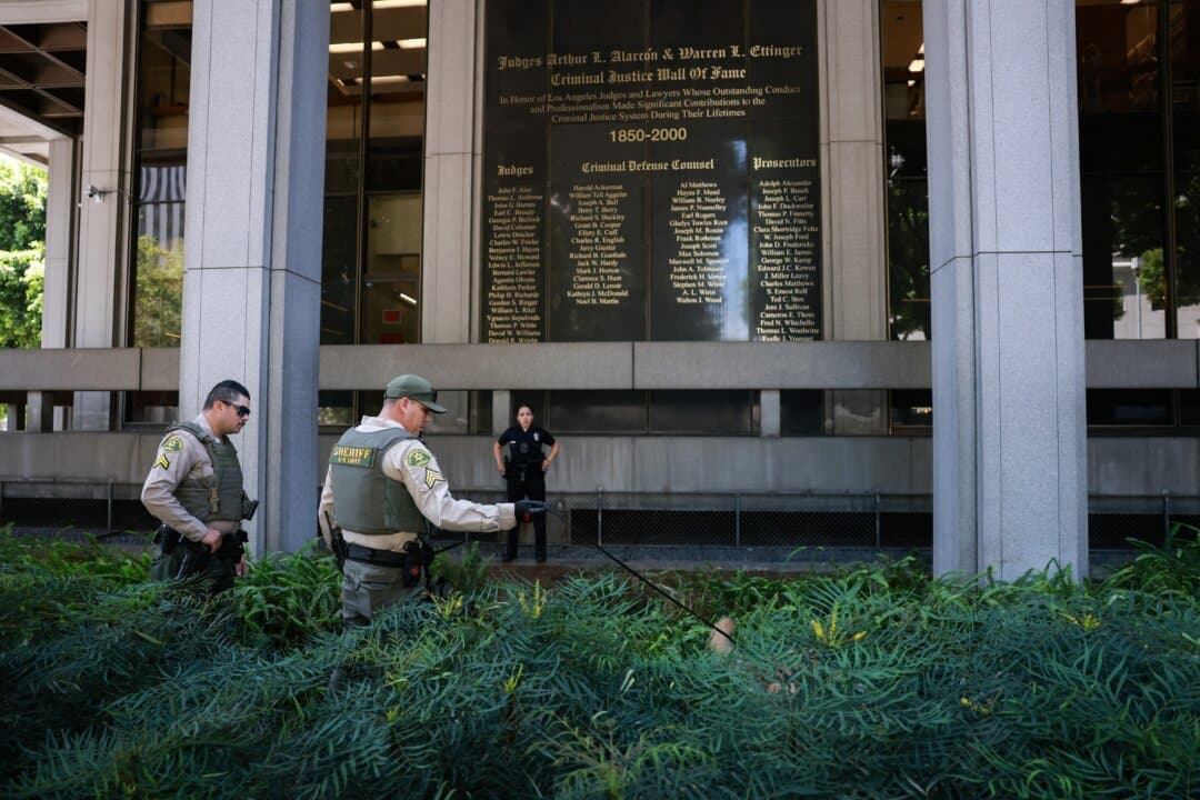 A Los Angeles County sheriff and his dog search for a suspected bomb outside Superior Court ahead of U.S. singer D4vd's arraignment in Los Angeles on April 20, 2026. D4vd, whose real name is David Burke, was arrested in connection with the killing of a teenage girl whose dismembered body was found in the trunk of a car registered in the artist's name, police said on April 16. (Patrick T. Fallon/AFP via Getty Images)