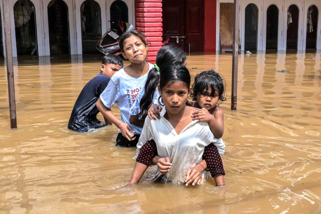 Children wade through floodwaters after heavy rain in Guwahati, India, on April 20, 2026. (Biju Boro/AFP via Getty Images)