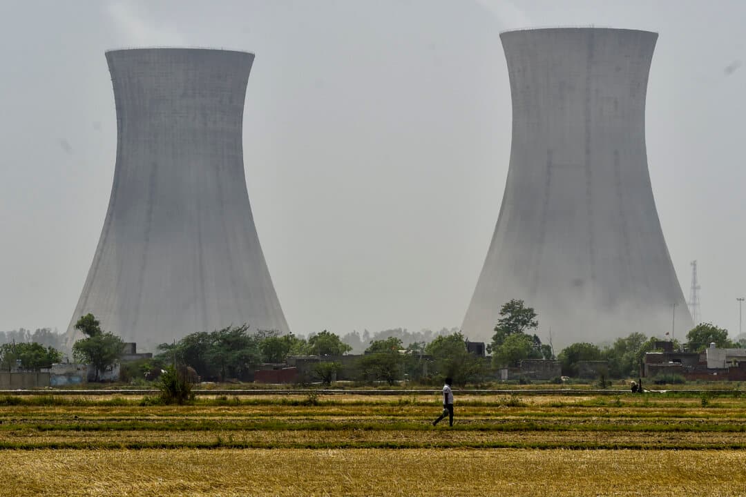A man passes through a thermal power plant with cooling towers in an industrial area in the outskirts of New Delhi on April 21, 2026. India, which imports roughly 88 percent of its crude oil and had been steadily expanding purchases of discounted Iranian barrels before the conflict escalated, now faces mounting pressure to secure alternative supplies as tanker insurance costs and shipping routes through the Persian Gulf come under renewed strain. (Ritesh Shukla/Getty Images)