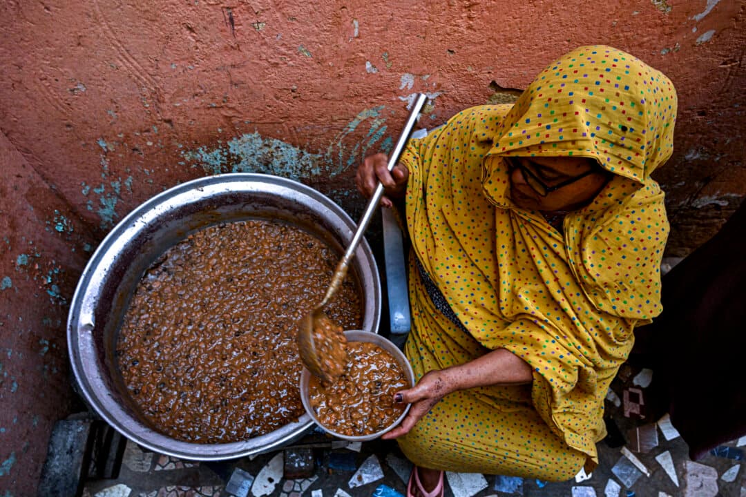 A Sudanese woman prepares a free meal canister at the home of the founder of the Community Kitchen initiative in Omdurman on April 21, 2026. The top United Nations official in Sudan told AFP on April 16 that the country, facing the world's largest humanitarian crisis, has been abandoned as the war between the army and the paramilitary Rapid Support Forces enters its fourth year. (Khaled Desoiki/AFP via Getty Images)