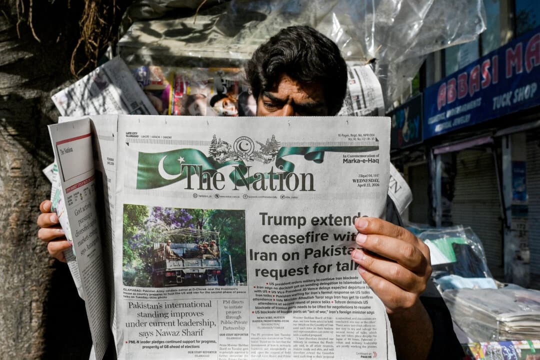 A man reads a newspaper with a front page article referring to anticipated U.S.–Iran peace talks, at a stall in Islamabad on April 22, 2026. Pakistani Prime Minister Shehbaz Sharif thanked President Donald Trump for extending a ceasefire with Iran and indefinitely pushing back the end of the two-week truce, with Tehran silent on the decision. (Asif Hassan/AFP via Getty Images)