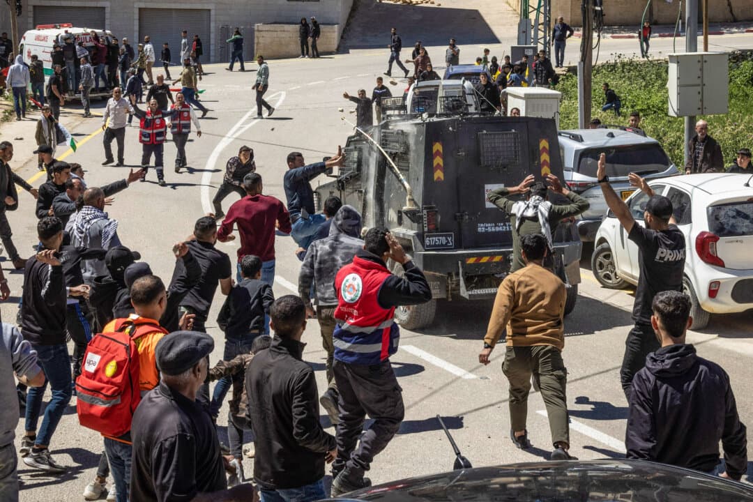 Mourners attack an Israeli police armored vehicle as it drives through the funeral procession of a teenager in Al-Mughayyir, east of Ramallah in the West Bank, on April 22, 2026. The Palestinian Authority said Israeli settler gunfire killed two Palestinians, including 14-year-old Aws Hamdi Al-Naasan and 32-year-old Jihad Marzouq Abu Naim on April 21. The Israeli military said it was reviewing the incident. (John Wessels/AFP via Getty Images)