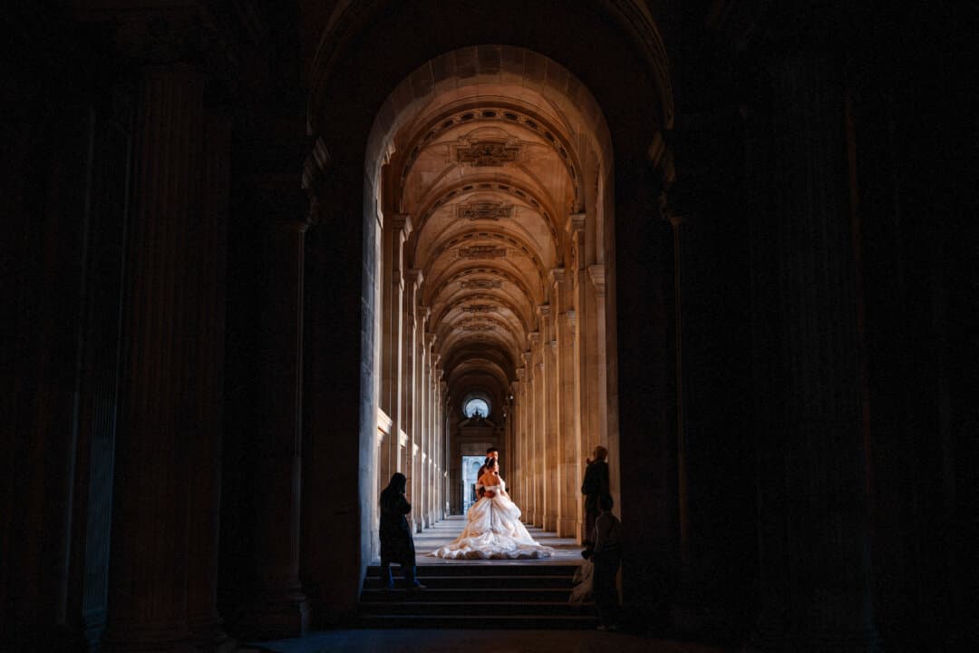 A bride and groom pose for a photo at the Louvre Museum in Paris on April 22, 2026. (Dimitar Dilkoff/AFP via Getty Images)